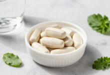 Magnesium glycinate supplement capsules in a white bowl on a marble countertop.