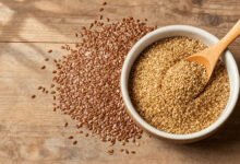 Flax seeds in whole and ground form displayed on a rustic wooden table surface.