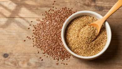 Flax seeds in whole and ground form displayed on a rustic wooden table surface.
